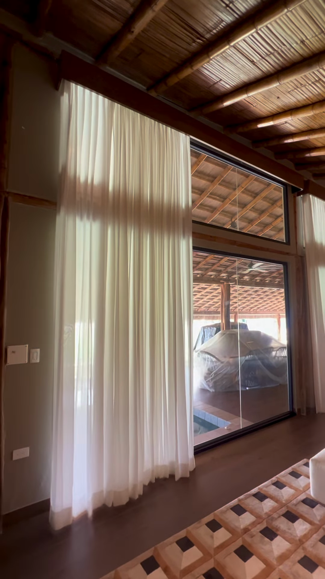 Cortinas textiles junto a un sofá y techo de madera