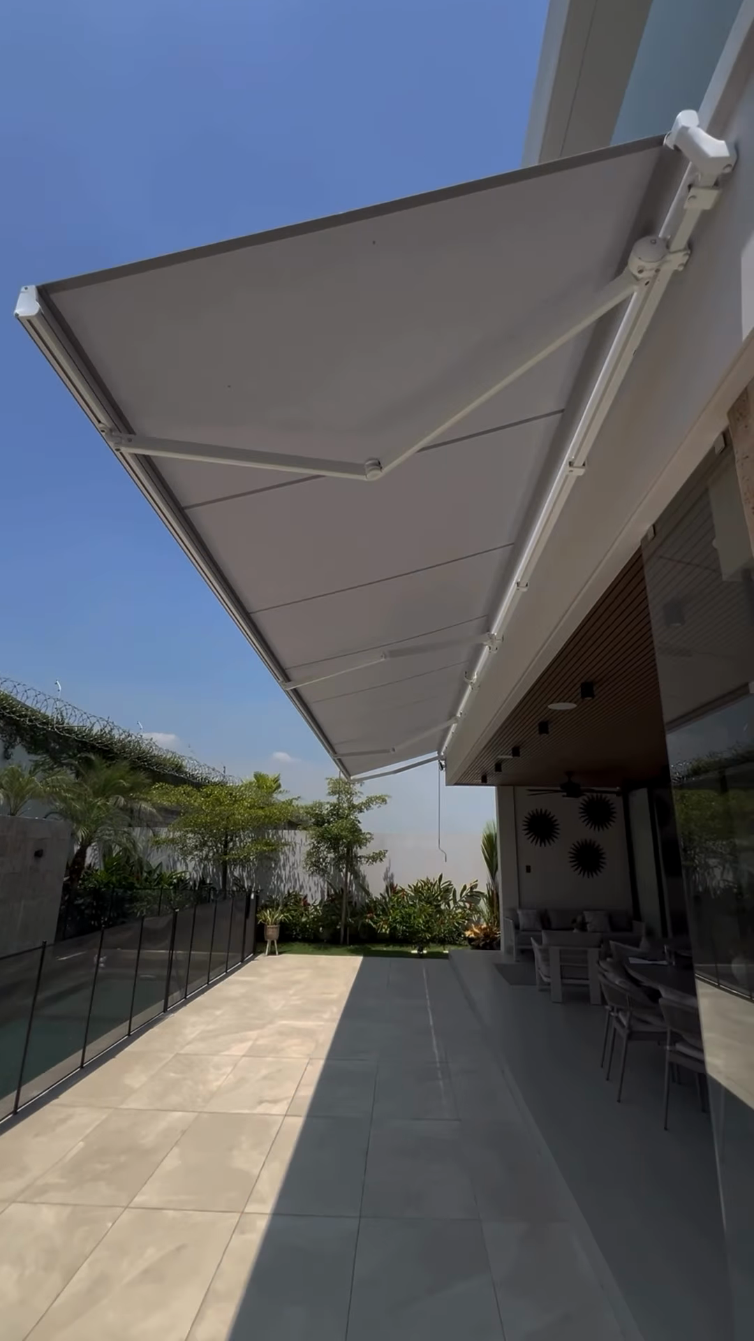 Toldo proyectante desplegado junto a una fachada